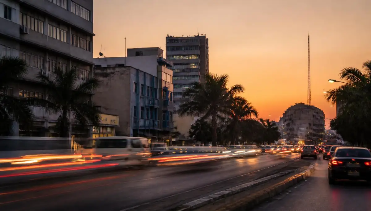 A Maputo avenue at dusk with traffic and palm trees